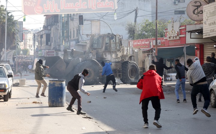 Jenin (-), 26/01/2023.- Palestinians throw stones amid clashes with Israeli troops during a raid in Jenin, West Bank, 26 January 2023. At least nine Palestinians were killed, including an elderly woman, during clashes in Jenin on 26 January, according to the Palestinian Health Ministry. Israeli security forces said they conducted a 'counterterrorism operation' in the center of Jenin. (Terrorismo) EFE/EPA/ALAA BADARNEH