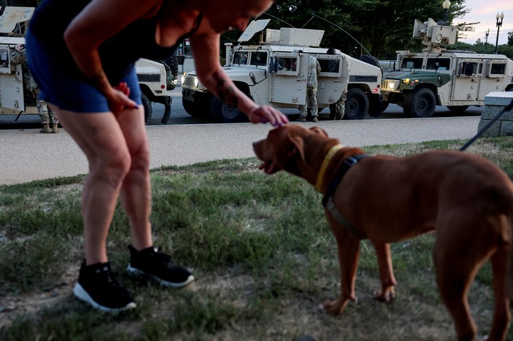 A woman pets a dog as people enjoy a night out at the National Mall, near where U.S. Army National Guard Humvees are parked by the Washington Monument after U.S. President Donald Trump announced a federal takeover of the Metropolitan Police Department under the Home Rule Act to assist with crime prevention in the nation's capital, Washington, D.C., U.S., August 12, 2025. REUTERS/Jonathan Ernst